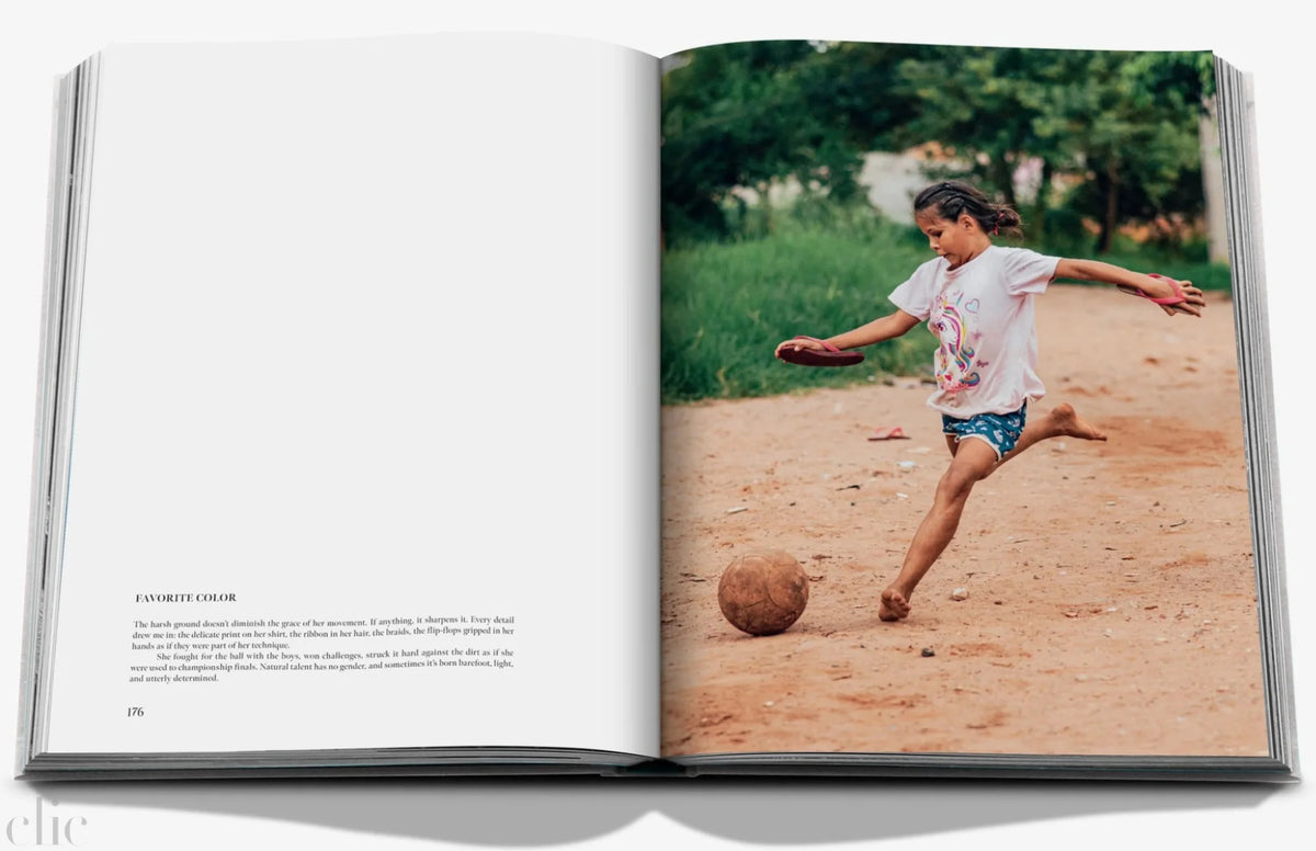 Open book showing a photograph of a child playing football on a dirt path.