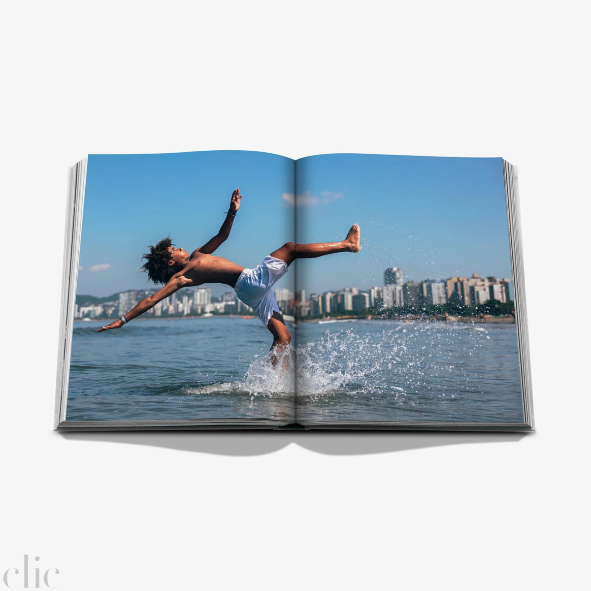 Open book showing a person diving into water with a cityscape in the background