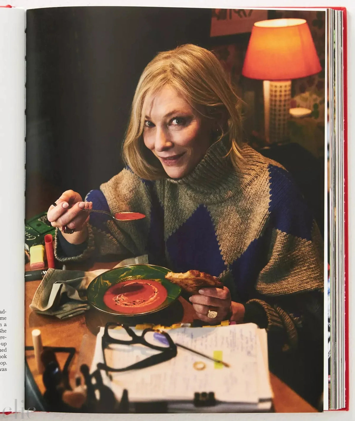 Open book showing a woman eating at a table with a lamp in the background