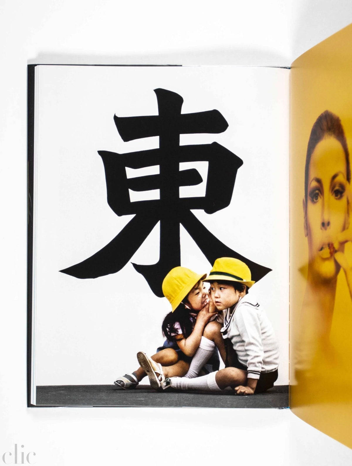 Two children in yellow hats sitting together with a large black Chinese character on a white background.