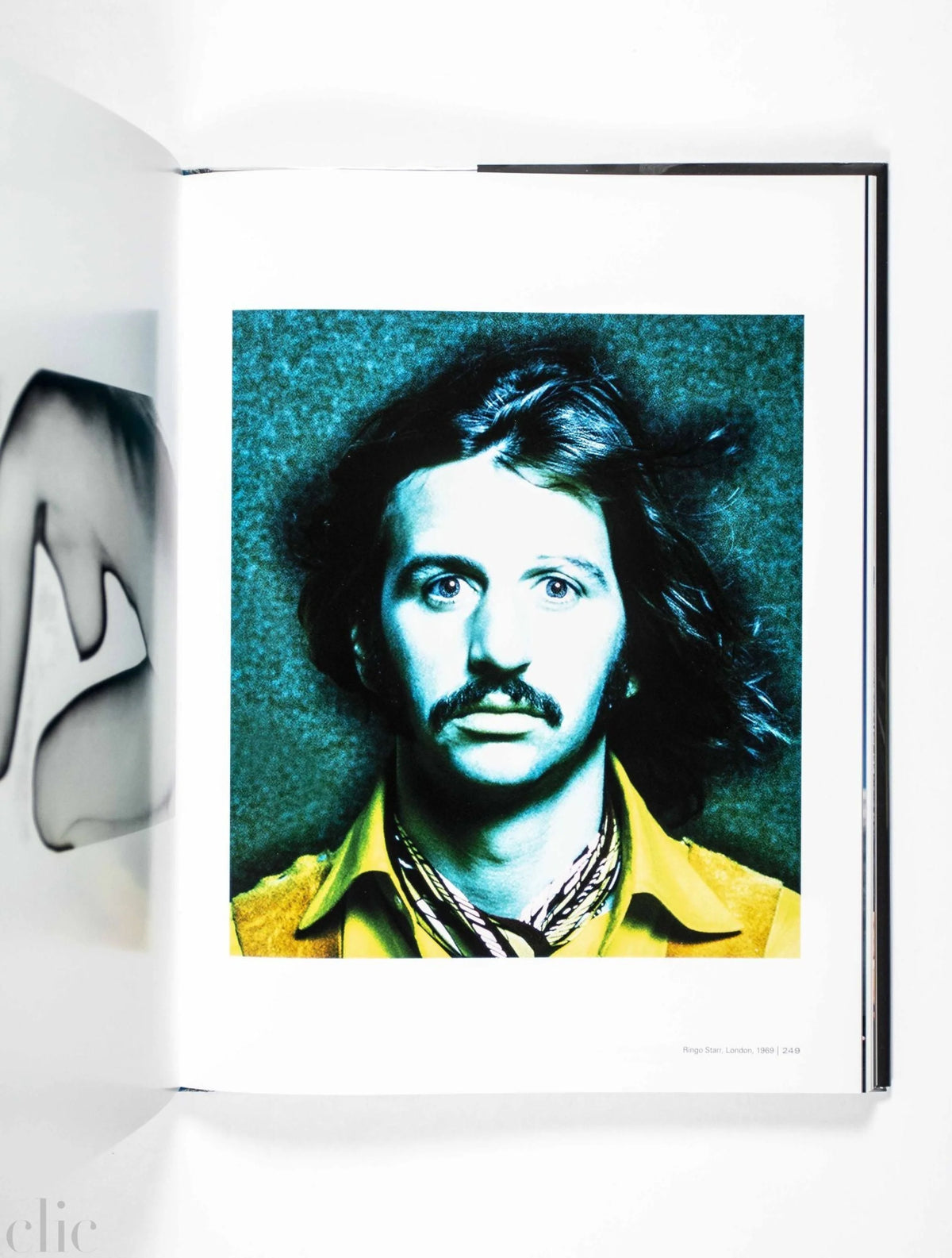 Book open to a page with a portrait of Ringo Starr with long hair and a mustache, wearing a yellow shirt.