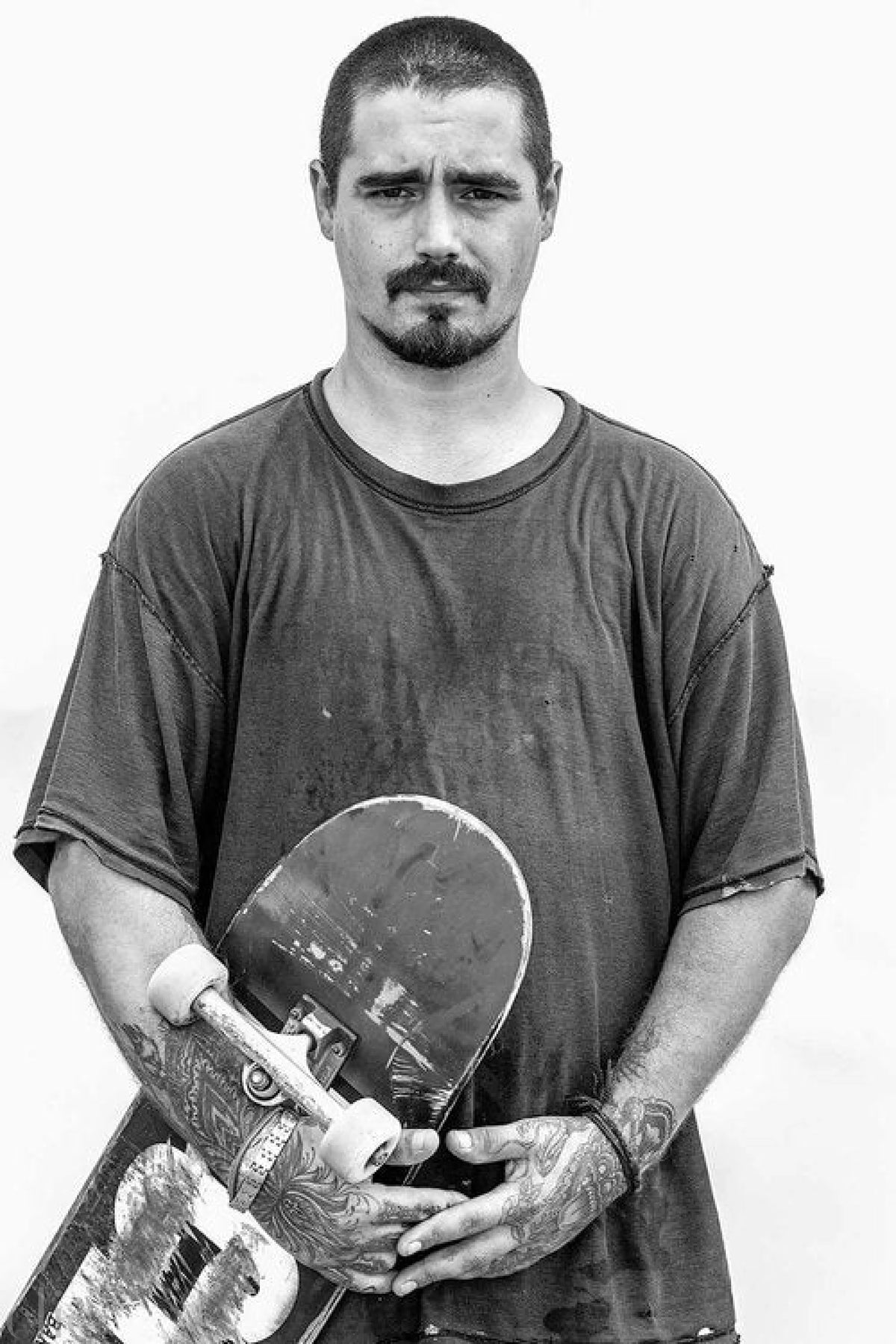 Man holding a skateboard against a white background