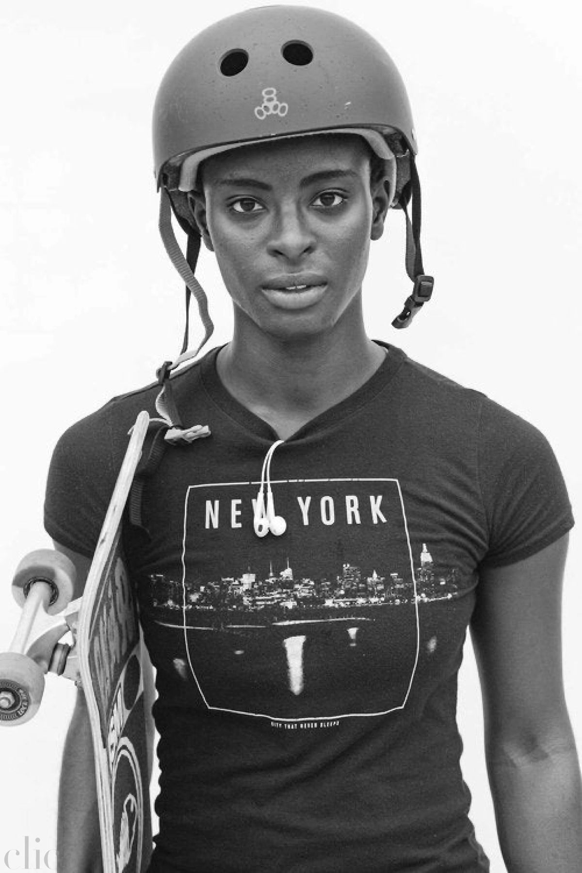 Person wearing a helmet and 'New York' t-shirt holding a skateboard
